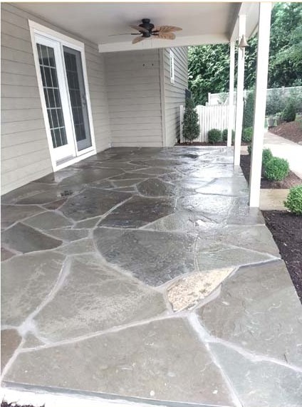 Completed wet-laid natural flagstone patio beneath a covered outdoor living area