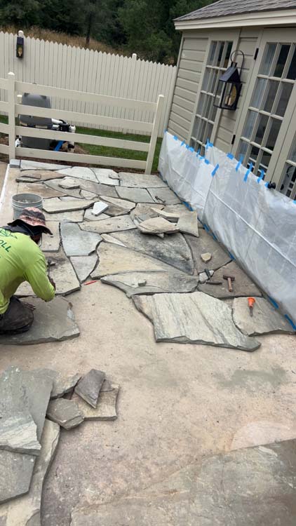 Wet-laid natural flagstone patio installation in progress under a covered porch